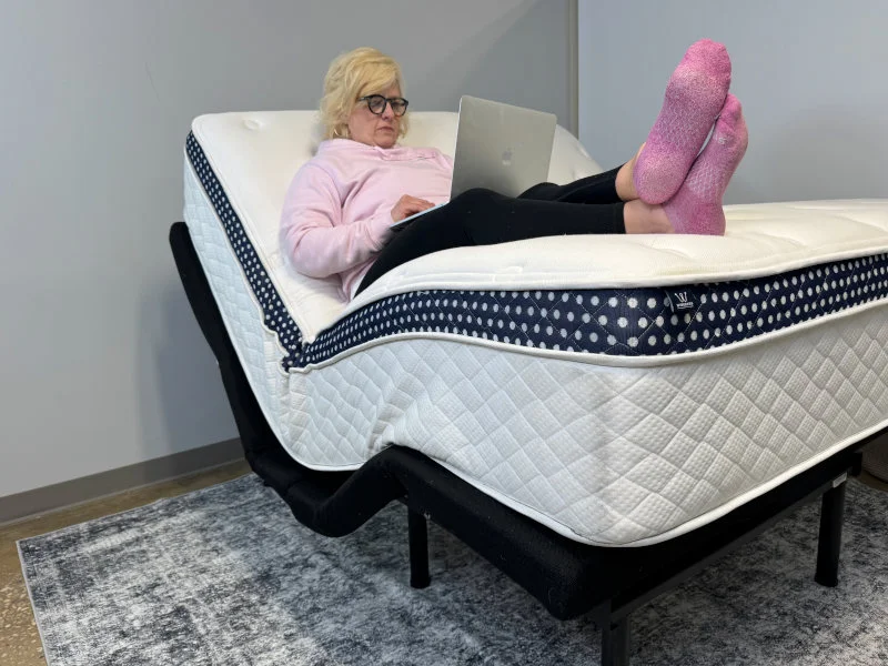 Our tester assessing the WinkBed Plus on an adjustable bed frame.