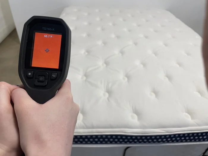 A closeup of someone using a thermal gun to measure the WinkBed's neutral temperature. The screen reads 65.7 degrees.