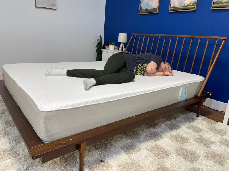Our tester side-sleeping on a Boring Hybrid Mattress