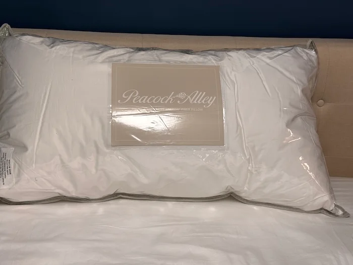 A Peacock Alley Down Alternative Pillow sitting on a bed in its packaging.