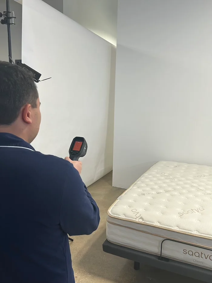 A man aiming a thermal gun at the Saatva mattress to read its neutral temperature.