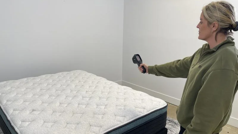 A person takes temperature readings from a mattress.