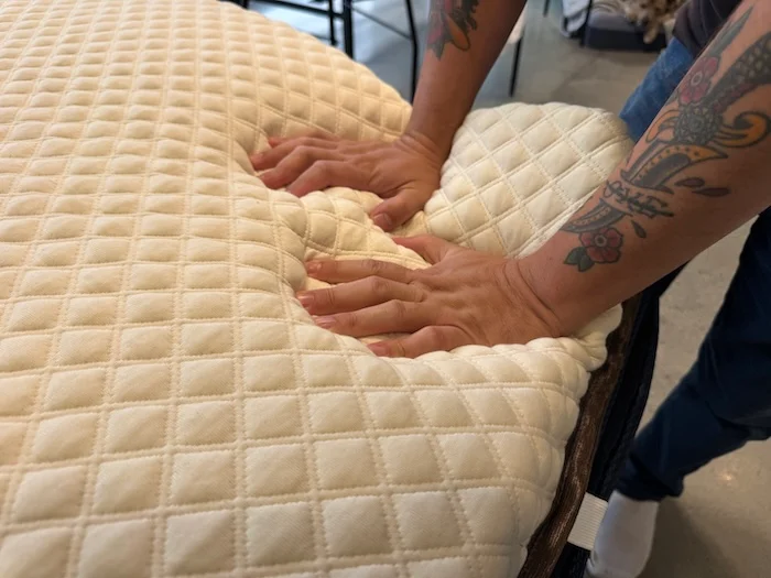 Our tester leans firmly into a mattress topper to evaluate responsiveness when the pressure is lifted.