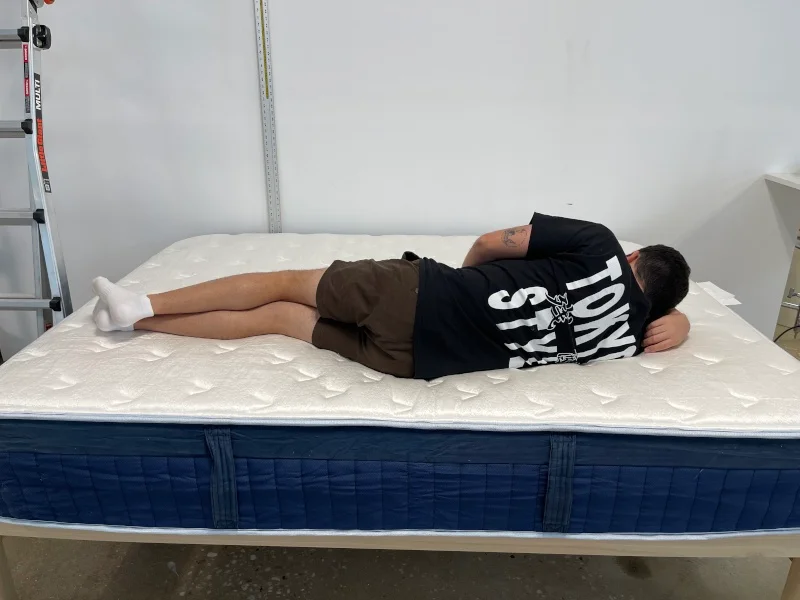 Our tester side-sleeping on a Glacier Summit Hybrid Mattress