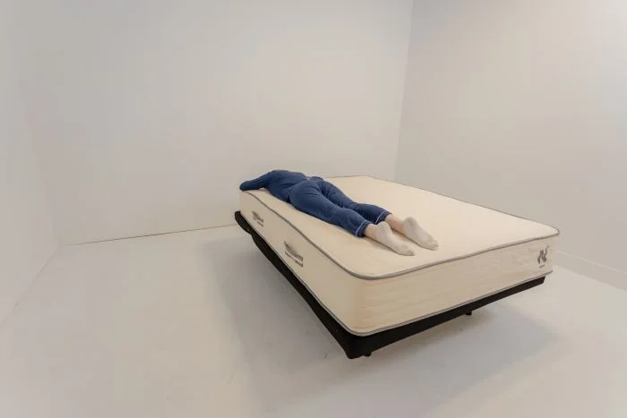 A woman stomach-sleeping on the Nolah Natural mattress.