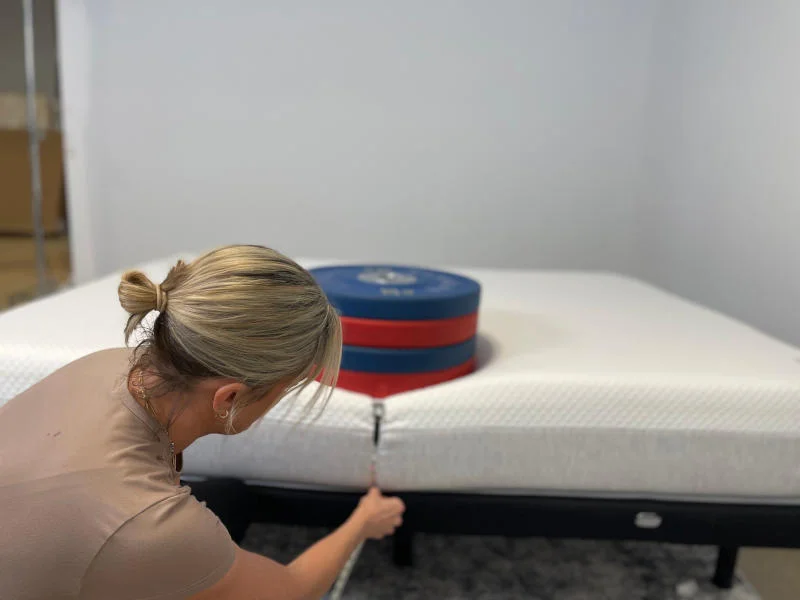 Our tester measuring weight plates on the edge of the Nolah Signature Mattress