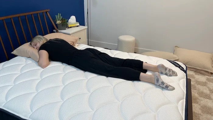 A woman sleeping on her stomach on the DreamCloud mattress.