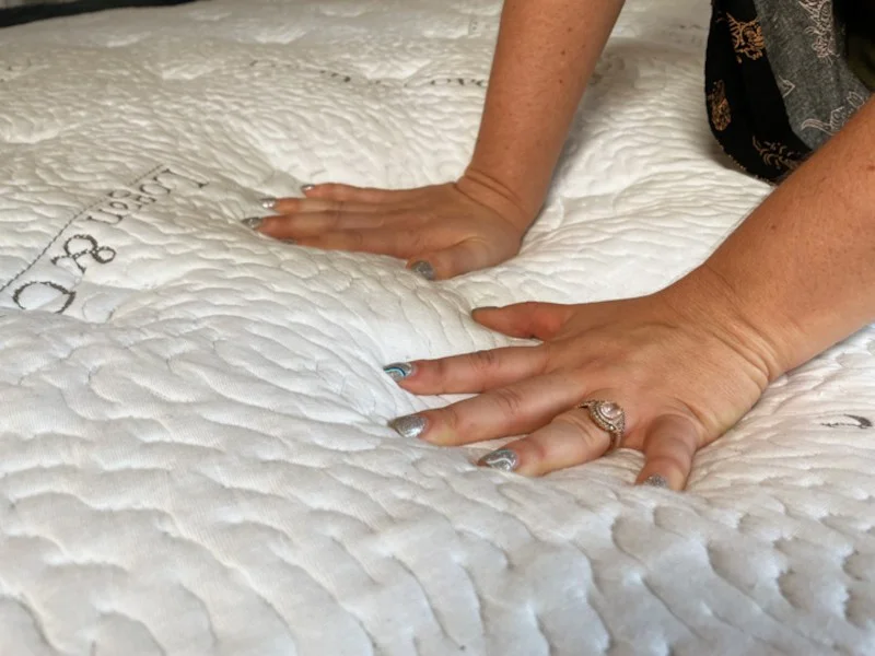 A hand is pressed down into a Logan & Cove Frontier mattress