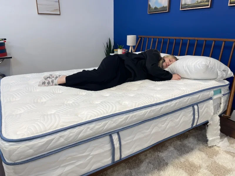 Our tester Riley Otis side-sleeping on the DLX Premier Hybrid