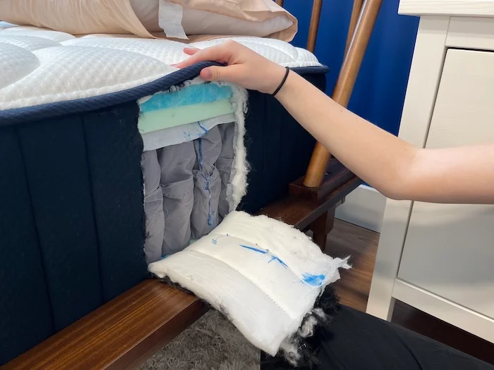 A small section of the DreamCloud mattress has been cut out of its side to expose the bed's layers.