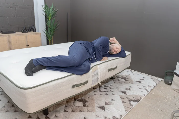 A man lying on the Avocado Green mattress in the side-sleeping position.