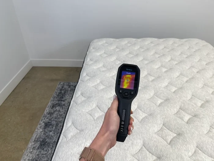 A closeup of someone using a thermal gun to take the temperature of the Helix Dusk Luxe. The screen reads 71.3 degrees.