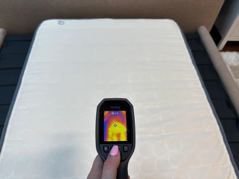 A mattress tester using a thermal gun to measure the surface temperature of the Birch Kids bed.