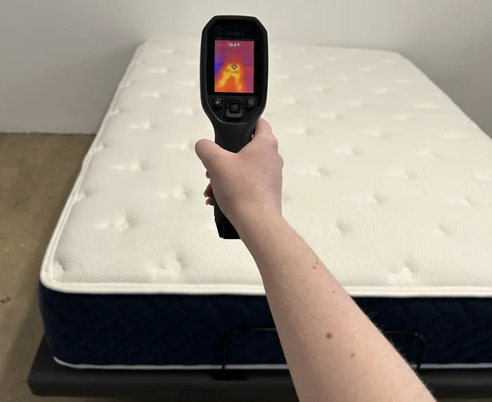 A closeup of a tester aiming a thermal gun at the Brooklyn Bedding Signature Hybrid mattress in order to get its temperature.
