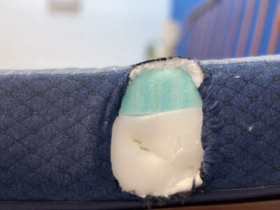 A close-up of the layers of the BB Kids mattress. A small section has been cut out of the side to show the foam underneath.