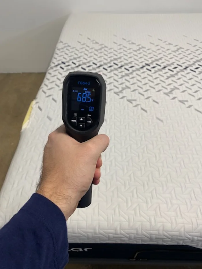 A closeup of someone using a thermal gun to read the neutral temperature of the Nectar Luxe Memory Foam mattress. The screen reads 68.5 degrees.