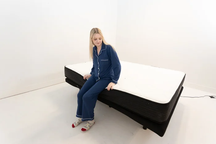 A woman sitting on the edge of the Plank Firm mattress to test out its edge support.