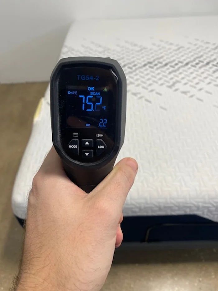 A closeup of someone using a thermal gun to read the temperature of the Nectar Luxe Memory Foam mattress after 5 minutes of someone lying on it. The screen reads 75.2 degrees.