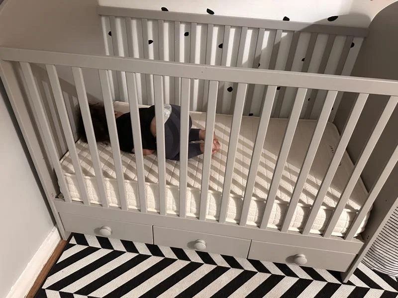 child curled up on a avocado luxury crib mattress