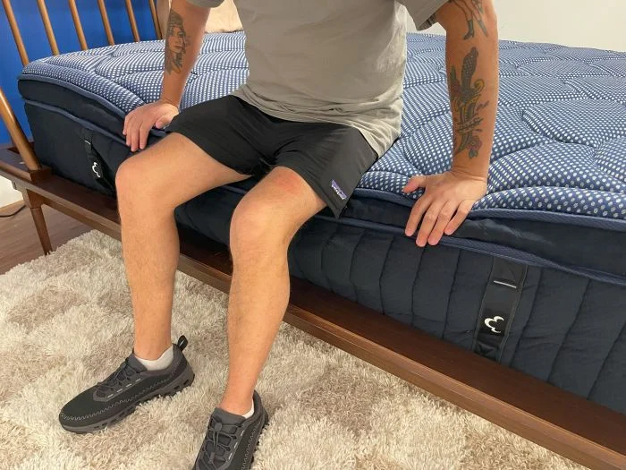 A man sits on the edge of the Dreamcloud Luxe Hybrid