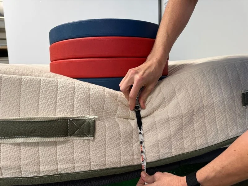 Our tester uses weight plates to assess edge support on the Avocado Eco Organic Mattress