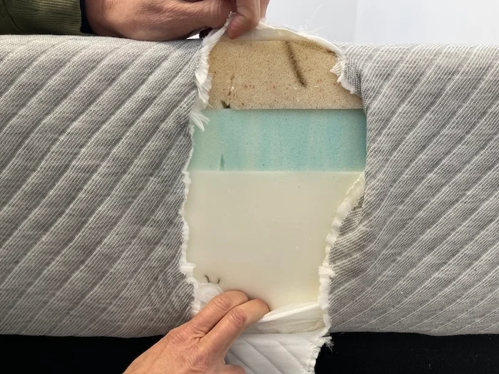 A closeup of the the side of the Leesa mattress. The cover has been cut away, showing three layers of foam underneath.