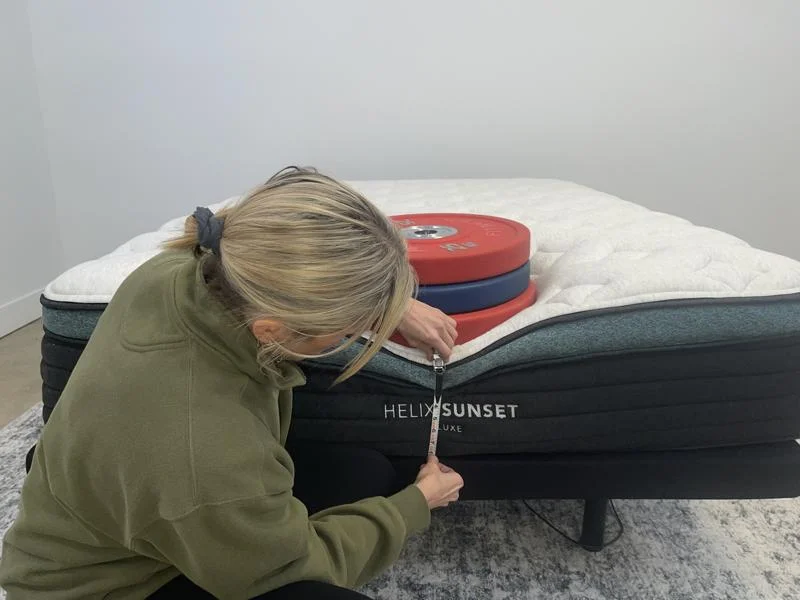 Our tester measuring weight plates on the edge of the Helix Sunset Luxe Mattress