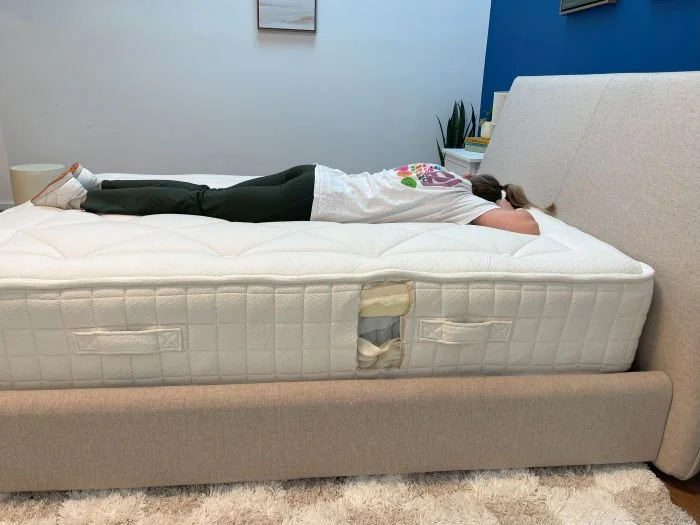 A woman lying on her stomach on the Avocado Luxury Organic mattress.