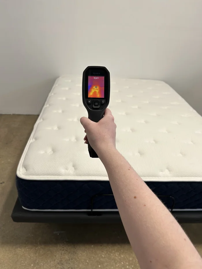 A closeup of someone aiming a thermal gun at the Brooklyn Bedding Signature Hybrid mattress in order to get its temperature.
