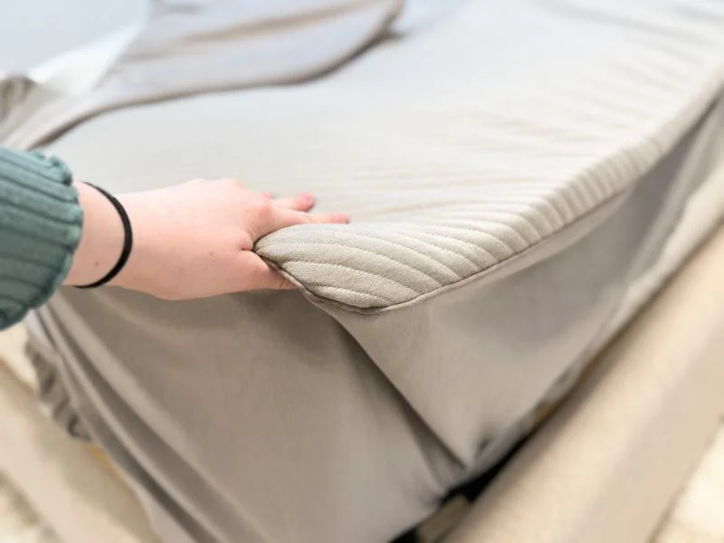 Our tester takes a moment to feel the mattress topper materials of Orion Sleep System.