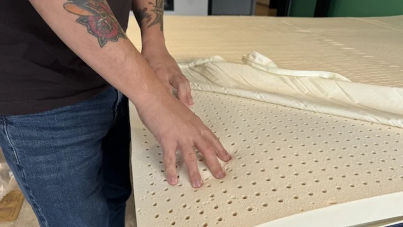 Our tester touches the latex insert in a Silk & Snow Organic Mattress Topper