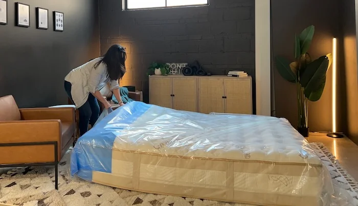 A woman about to remove the plastic wrapping from the Saatva Rx mattress.
