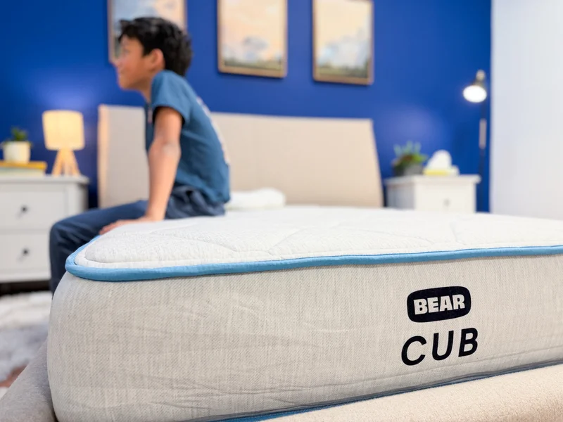 A mattress tester tests the edge support on the Bear Cub mattress.