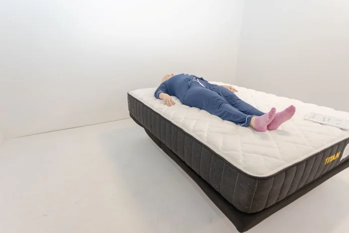 A woman lays on her back on the Titan Plus mattress