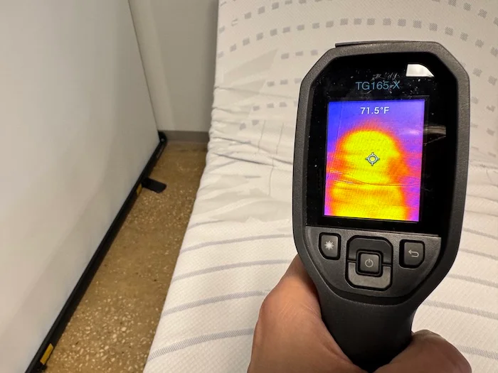 A closeup of a thermal gun measuring the temperature of the BodiPedic 12" after 5 minutes of someone lying on it. The screen reads 71.5 degrees.