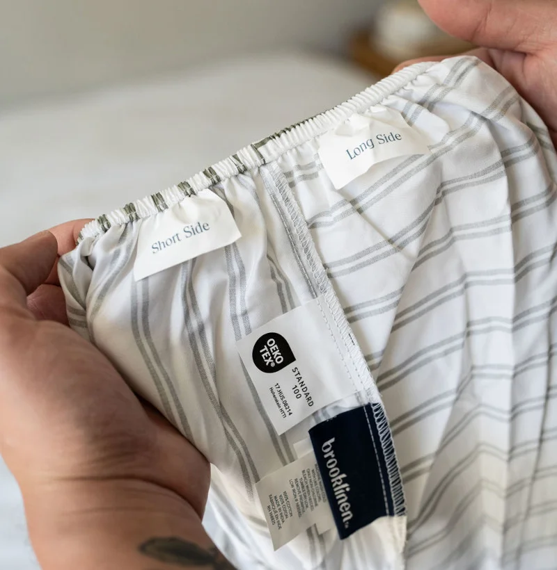 Our tester inspecting the tags on Brooklinen Luxe Sateen Sheets