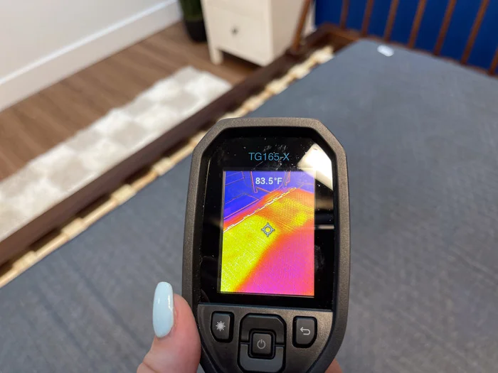 A closeup of a thermal gun reading of the temperature of the BB Kids mattress after someone has rested on it for 5 minutes. The screen reads 83.5 degrees.