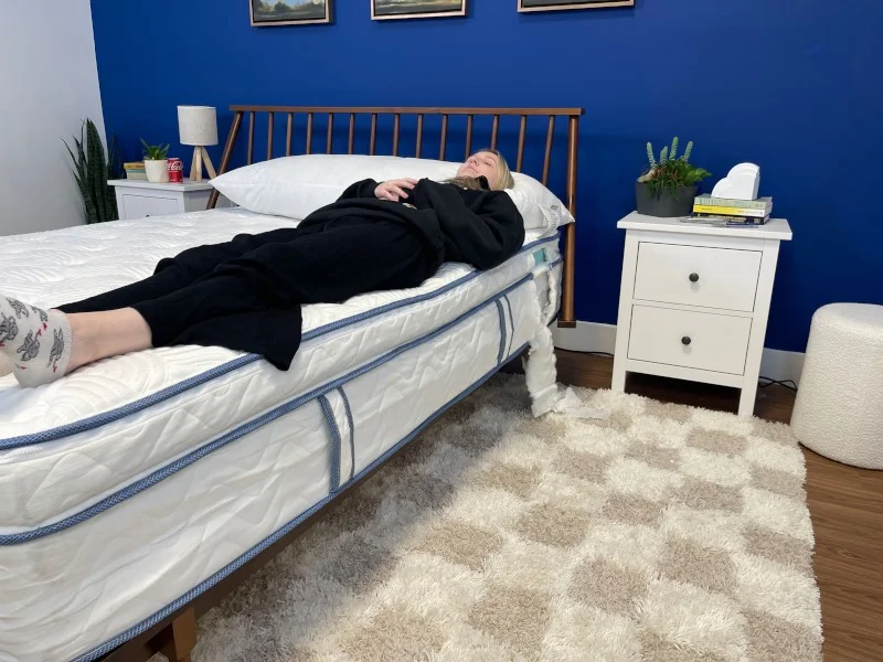 A person lays along the edge of a mattress to assess edge support.