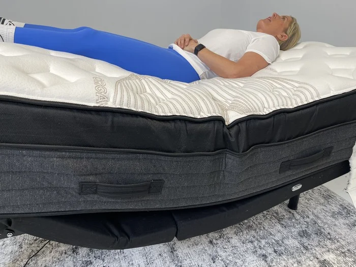 A woman lying on the Nolah Evolution mattress while it's on top of an adjustable base.