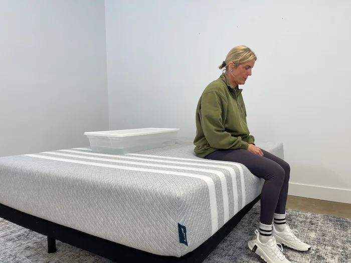 A woman sitting on the edge of the Leesa Original mattress.