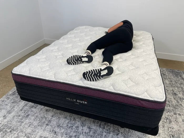 A woman lying on the Helix Dusk Luxe and rolling over to her side.