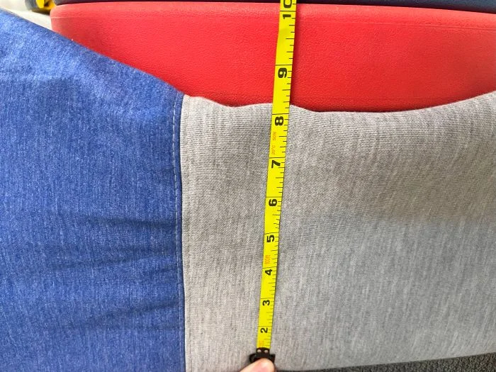 A stack of weights on top of a Casper The One mattress, with a tape measure measuring the sinkage.