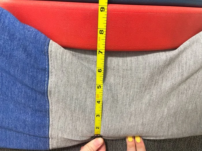 A stack of weights on top of a Casper The One mattress, with a tape measure measuring the sinkage.