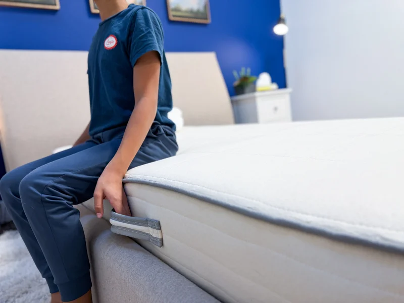 A mattress tester sits on the edge of the Nolah Nurture mattress.