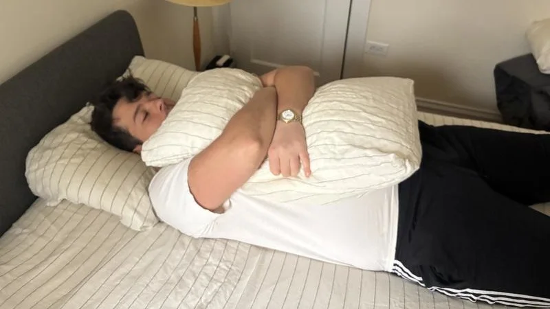 Our tester hugs a pillow while enjoying the Silk & Snow Flax Linen Sheets