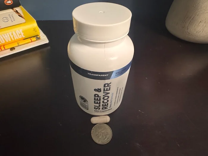 A Transparent Lap Sleep & Recover capsule is next to a quarter for size comparison.