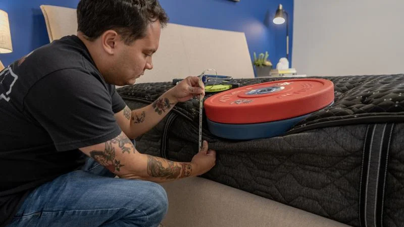 Our tester measures the sinkage from weight plates along the edge of the Beautyrest Black Mattress