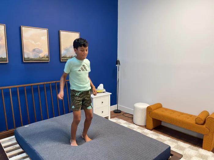 A 10-year-old boy jumping up and down on the BB Kids mattress to test its bounce.