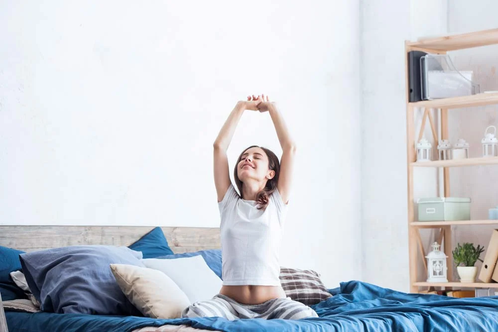woman stretching in bed after good night's sleep from following a bedtime routine