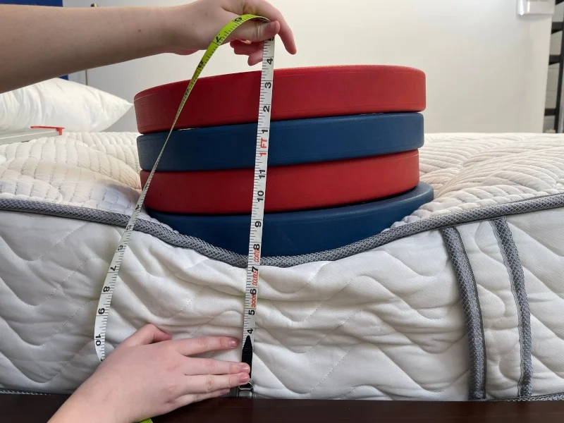 Our tester measuring weight plates on a DLX Classic mattress
